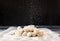 Dumplings on the Board, flour pours on top of a dark background