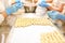 Dumplings manufacturing process. Hands of employers in blue rubber gloves and damplings on tray covered with wax paper