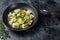 Dumplings Soup with Ravioli pasta in a bowl with greens. Black background. Top view. Copy space