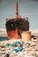 Dumpster and scattered plastic bottles on the beach. In the background is a ship, nose close-up. Vertical orientation