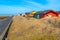 Dune, Germany - 02.27.2022: Colorful wooden cabins on sandy dunes with yellow grass on a beautiful sunny day of winter