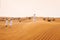 Dunes in desert, sand. In the distance are men in Arab national dress