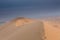 Dunes in the Khongoryn Els desert with blue sky and people at the top of the dune. Mongolia