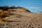 Dunes leading upwards, with a blue sky and grey clouds