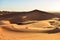 Dunes at sunset in the Sahara desert overlooking a Berber camp.