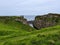 Dunseverick castle with green grass on rocky cliffs gloomy seascape background