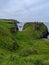 Dunseverick castle with green grass on rocky cliffs gloomy seascape background