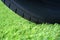 Durable artificial grass lawn concept with wheel tire on the green synthetic turf