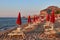 In dusk atmosphere closed parasols in front of the skyline of CefalÃ¹ with its famous rock montain