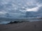 Dusk on the rocky beach with dark, gray, cloudy sky