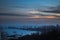 Dusk settles over harbor with silhouette of cranes against twilight sky. Industrial seascape at sunset, city skyline