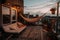 At dusk in the summer, a comfortable rooftop patio area with a lounging area, a hanging chair, and string lights is there