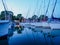Dusk view of moored sailing yachts on jetty in a port on a lake, calm summer blue evening view