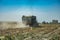 Dust behind a tractor with a trailer in the field