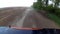 Dust rising from automobile wheels automobile driving on rural gravel road.