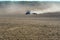 Dust from small tractor working in a field. sowing work on plowed land