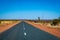 Dust storms besides dark road leading through red sanded Australian landscape towards Karijini National Park