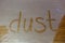 Dust written on dusty wooden surface partly cleaned