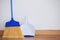 Dustpan and sweeping broom leaning against white wall