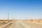 Dusty desert road in the Maranjab desert, in Iran, surrounded by sand and dry bushes