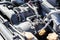 Dusty details of a flat-four boxer car engine compartment under the open hood. Alternator and intake manifold