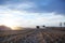 Dusty harvest farm machinery illuminated by sunset