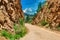 Dusty Mountain Road with Snow Capped Peak and Rock Walls