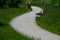 Dusty park path along the pond winding through a meadow. it leads to the bridge and the share of the way are long benches with woo