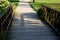 Dusty park path along the pond winding through a meadow. it leads to the bridge and the share of the way are long benches with woo