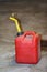 Dusty red plastic gas can with a yellow spout on a garage floor