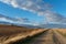 Dusty road through a beautiful grassy landscape in Andalusia in Spain