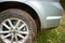 Dusty spoked wheel of a sedan parked in grass