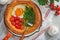 Dutch baby pancake. Fresh homemade Dutch Baby pancake with fried egg, tomato and green arugula in reed cast-iron pan on light gray