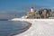 Dutch beach covered with snow and view at lighthouse Urk