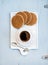 Dutch caramel stroopwafels and cup of black coffee on white ceramic serving board over light blue wooden backdrop