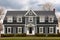 dutch colonial facade with enhanced dormer windows under gray sky