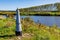 Dutch countryside with border marker between Belgium and Holland, Maas river and trees in background