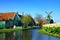 Dutch countryside with windmill, wooden houses and tulips along a canal, Zaanse Schans, Netherlands
