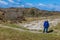 Dutch dune nature reserve with a woman in a blue jacket standing on a hiking trail surrounded by sandy hills