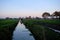 Dutch Frisian polder landscape scene with green pasture meadows, ditch, canal and migratory birds in v shape in the sky