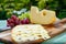 Dutch Maasdam hard cheese with holes, piece and sliced, served outdoor in green garden