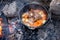 Dutch oven campfire cooking process - lamb and vegetables in a cast iron camp oven