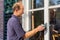 Dutch painter scours window frame with sander