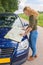 Dutch teenage girl reads road map on car hood