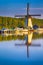 Dutch Windmill In Front of The Canal With Moored Motorboats Located in Traditional Village in The Netherlands. Shot at Kinderdijk