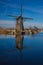 Dutch windmill reflecting in the canal water in Kinderdijk Holland