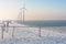 Dutch in winter with snow, fence and wind turbines
