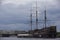 Dutch wooden fluyt merchant sailing ship of XVIII century with three wooden masts on a grey sky and clouds background