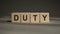 DUTY Word Written In Cubes on a black and grey background