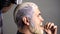 Dyed hair for a bearded hipster guy. Hairdresser applying dye to man hair. Hair coloring in gray color process. Process